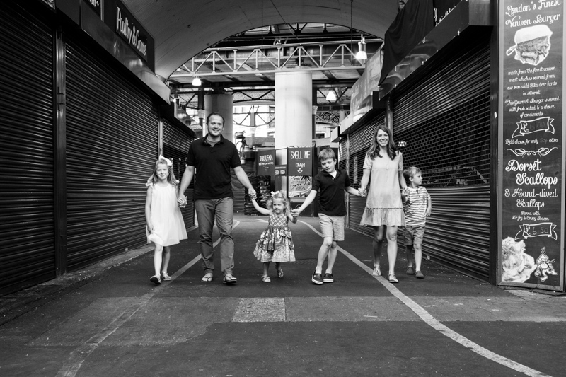 Mum. dad and four children walking hand in hand through Borough Market