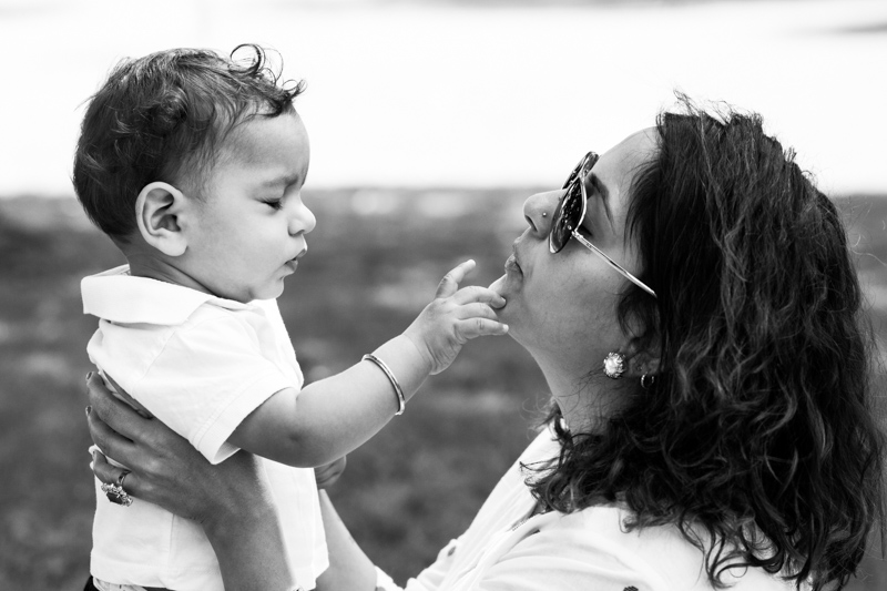Baby boy with his eyes closed, playing with his mum's face. 