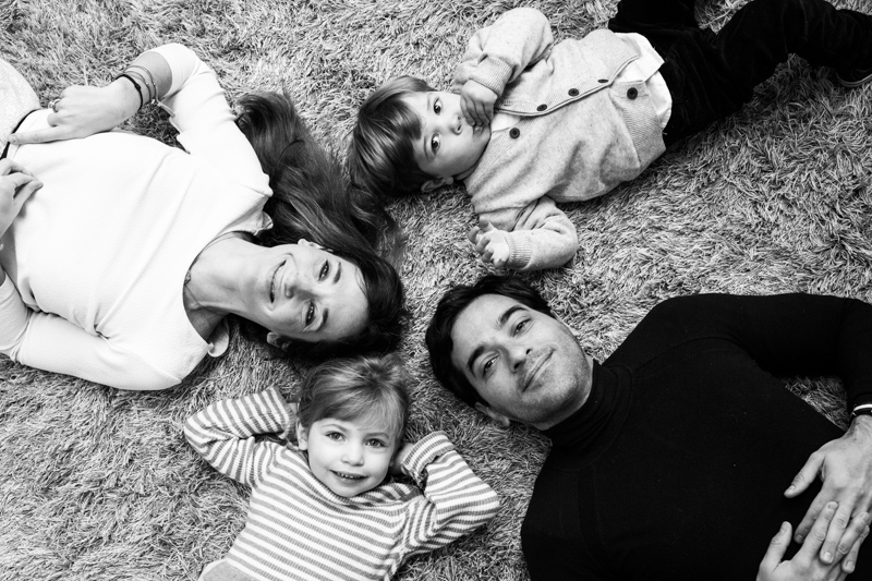 Family of four lying on a rug. 