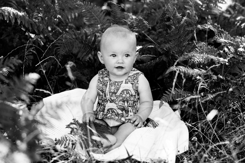 Baby girl sitting amongst some leaves