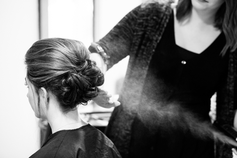 Hairdresser spraying hairspray onto lady's hair. 