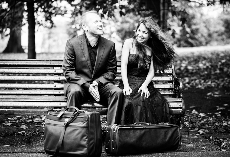 Man and lady sitting laughing on bench. 