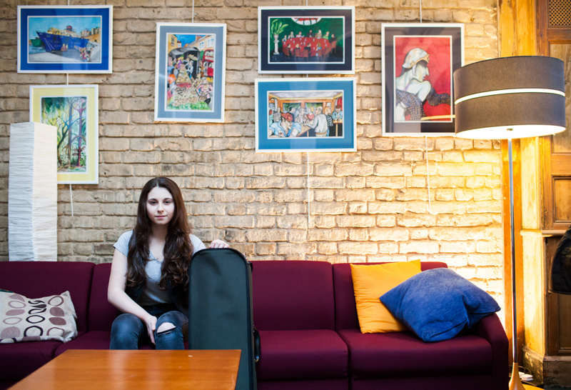 Lady sitting on sofa surrounded by pictures on wall. 