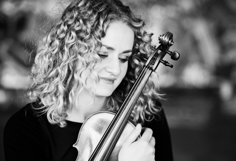 Lady with curly hair holding violin. 