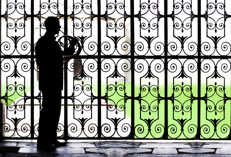 Silhouette of man playing French horn. 