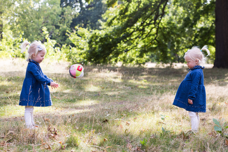Two little girls throwing a ball to each other. 