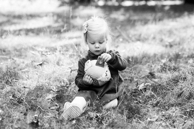 Little girl playing with a toy while sitting on the grass. 