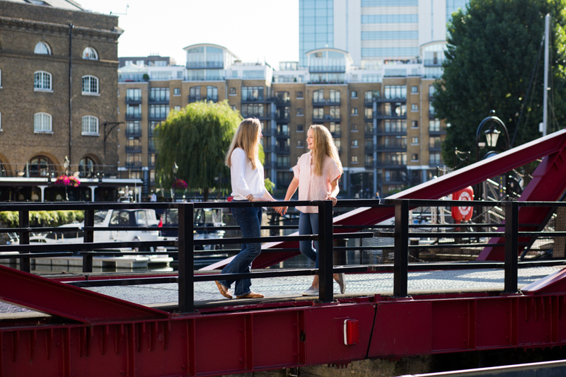 Mum and daughter looking at each other on red bridge. 