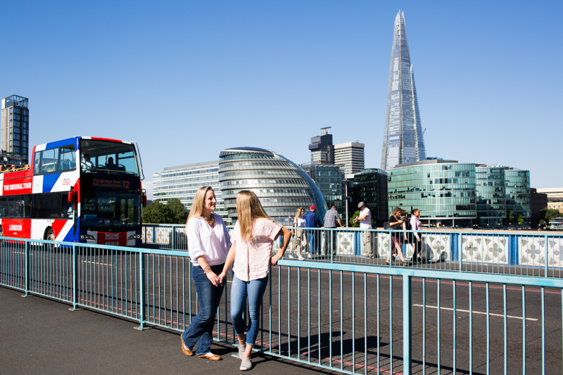 Mum and daughter looking at each other with the Shard and City Hall in the background. 
