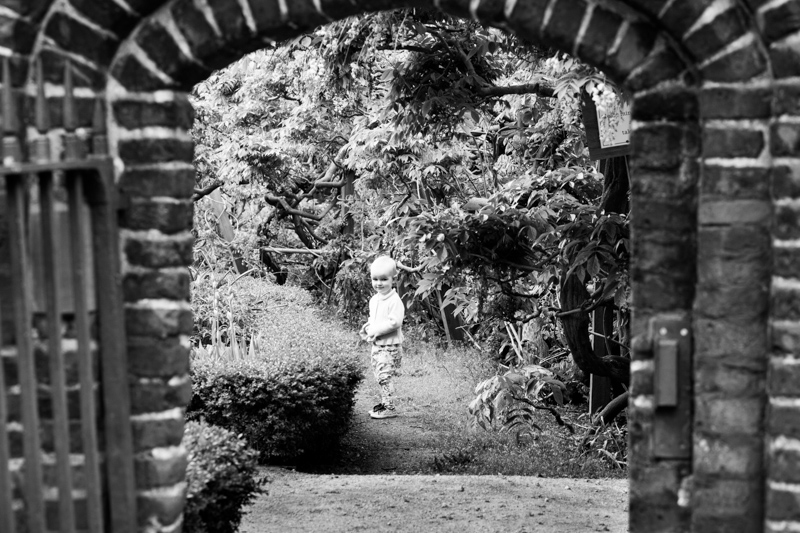 Little girl looking through brick doorway. 