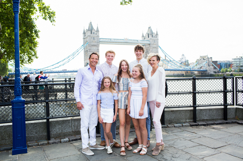 Family of seven smiling with Tower Bridge in the background. 