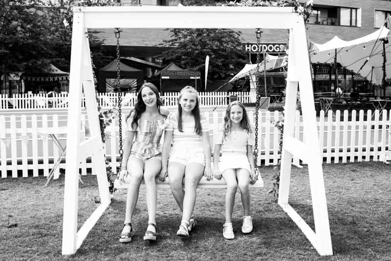 Three girls sitting on a swing chair. 