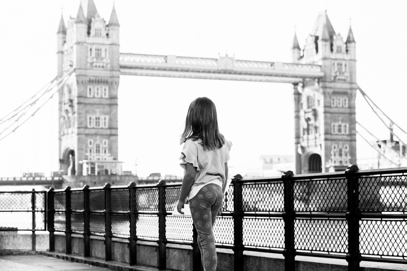 Girl looking across river at Tower Bridge.