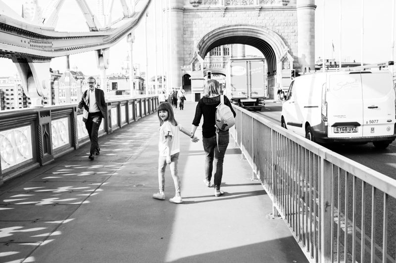 Girl walking across Tower Bridge looking behind her. 