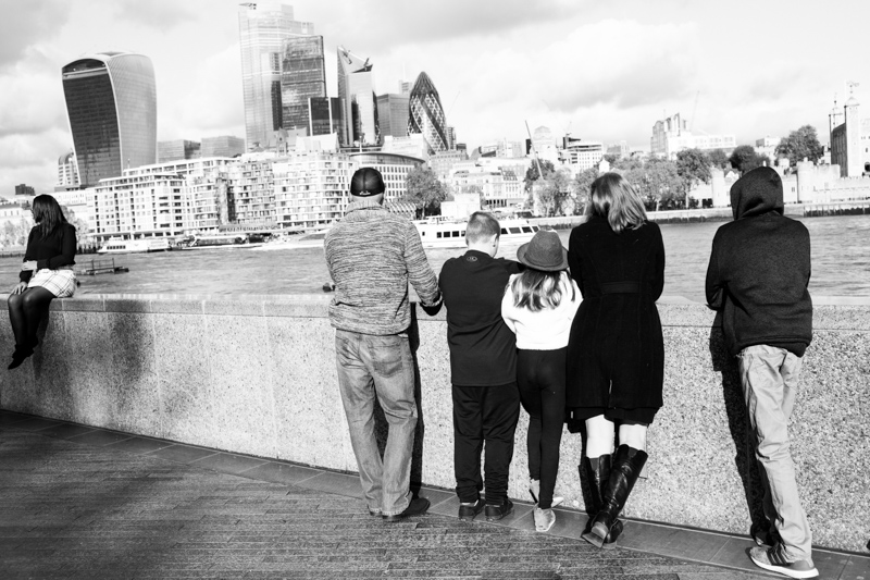 Two adults and three children looking across the River Thames to the City of London.