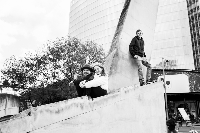 Three children sitting and standing on a high monument.