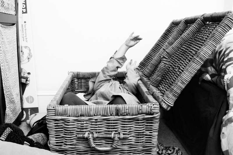 Little girl lying in a box with her hand up in the air.