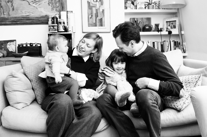Family of four cuddling and laughing on the sofa.