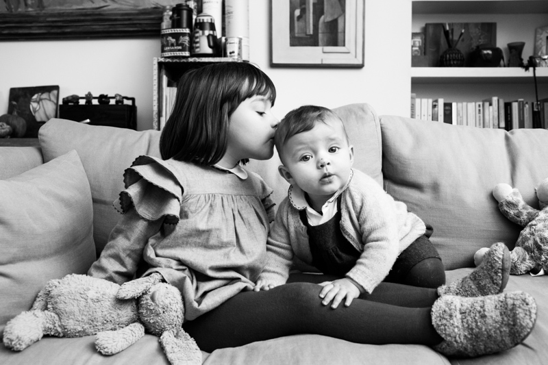 Girl kissing little baby on the head.