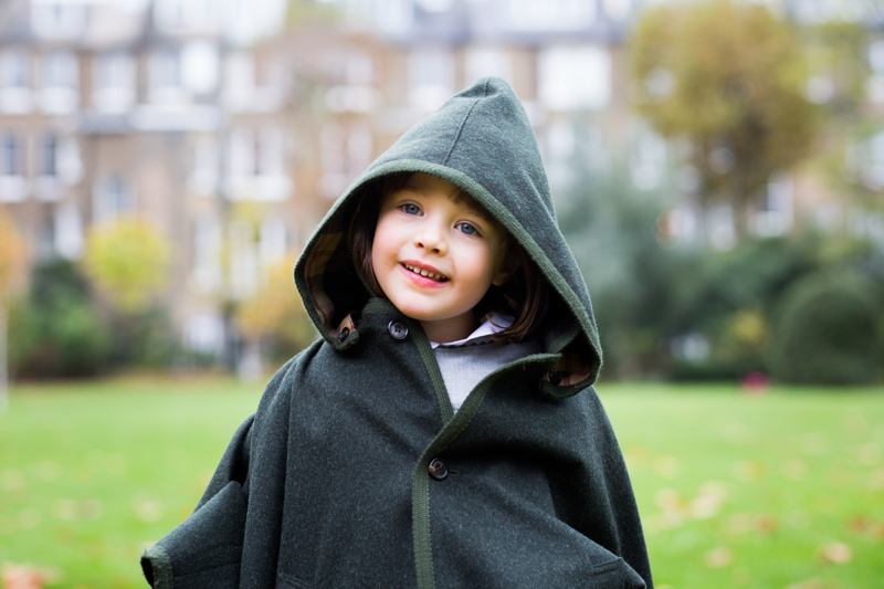 Smiling girl in green hooded cape.