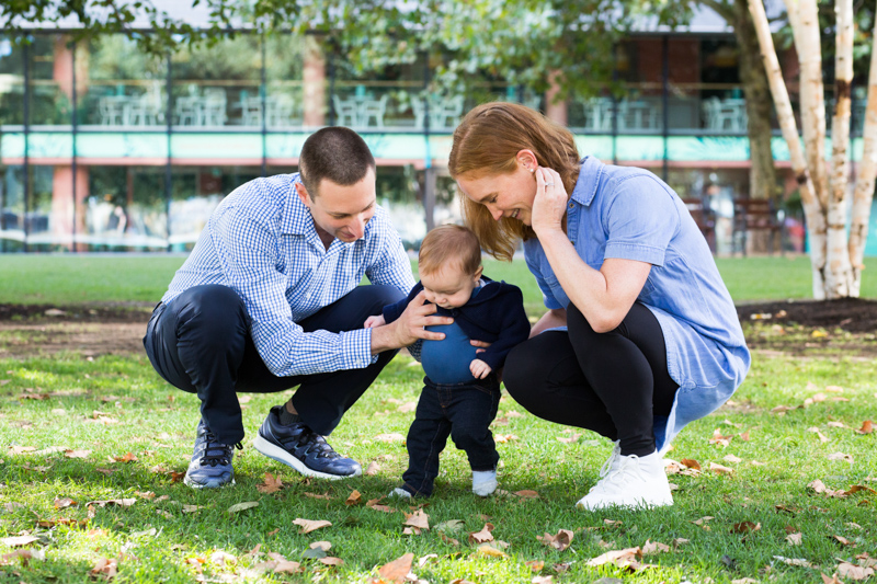 Mum and dad holding their baby while he tries to walk.