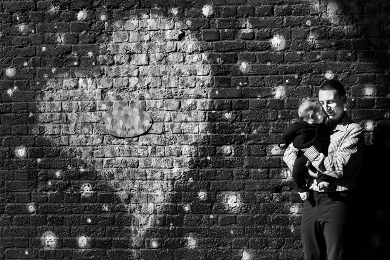 Man and little baby standing next to big heart on wall.