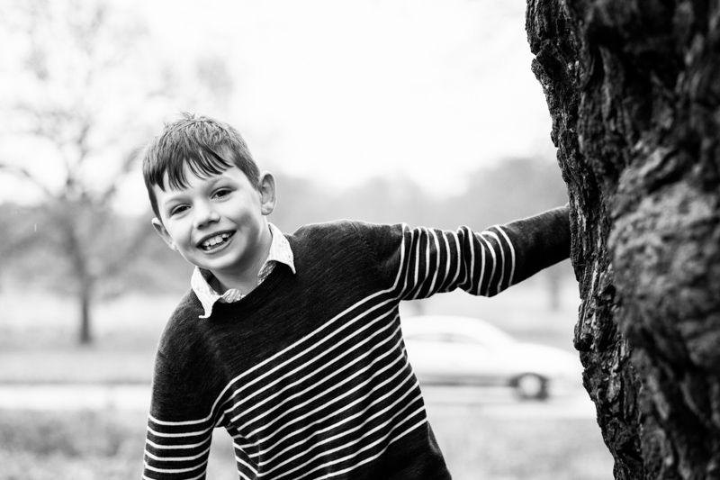 Boy with hand on tree smiling