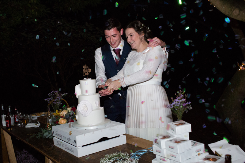 Wedding couple cutting cake surrounded by glitter