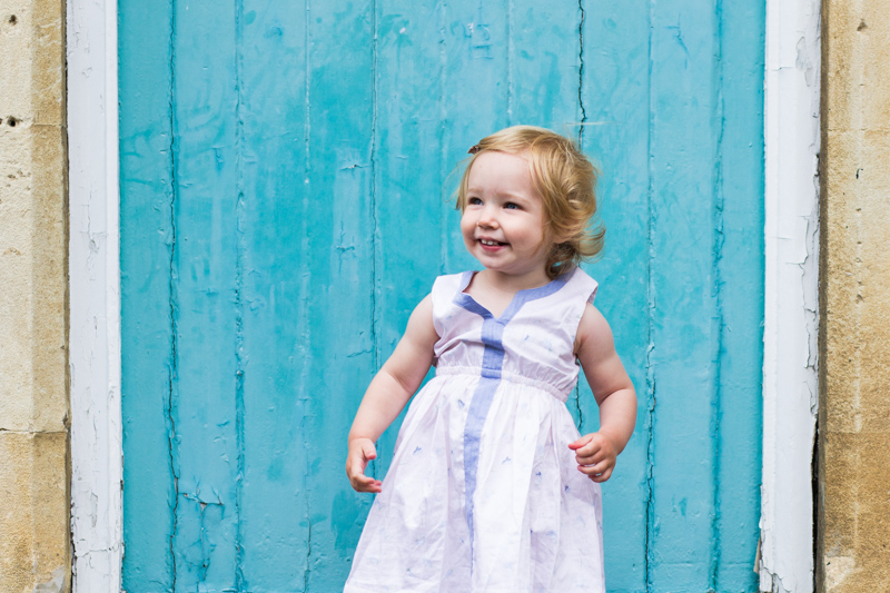 Little girl smiling in front of blue wall