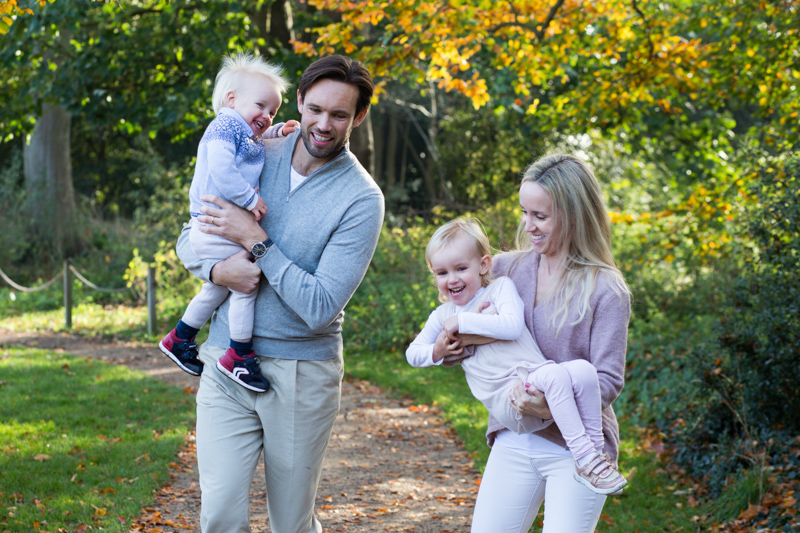 Family of four walking and laughing in front of Autumn colours