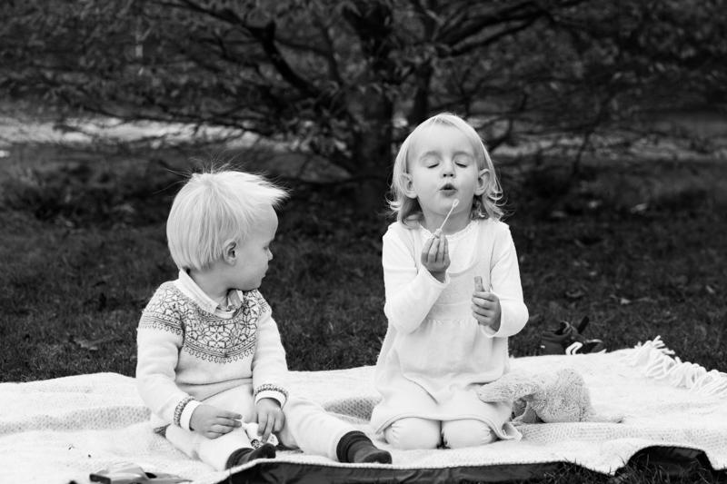 Girl blowing bubbles while little boy watches 