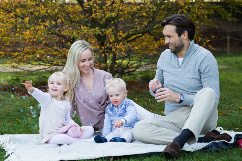 family of four sitting in front of Autumn tree