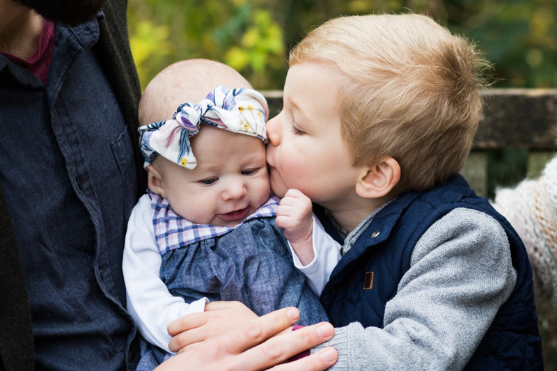 little boy kissing baby girl with headband. 
