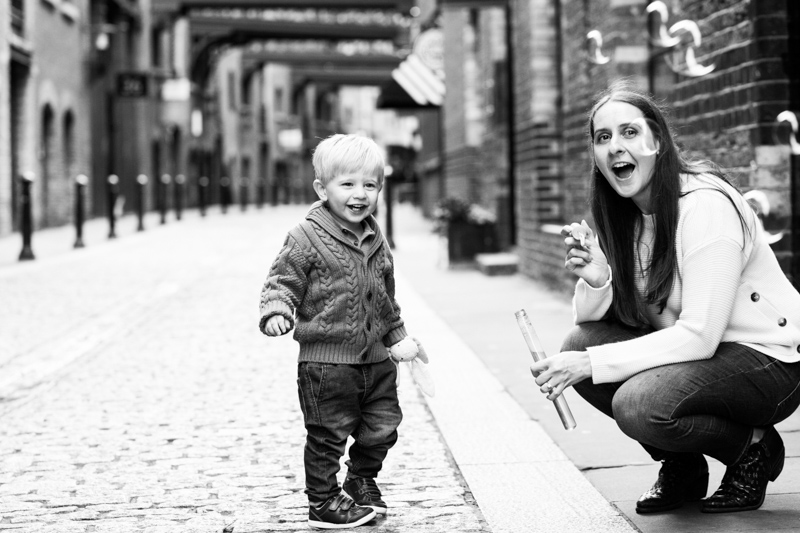 mum and son blowing bubbles in cobbled street. 