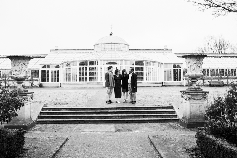 family of four standing in front of huge glasshouse. 
