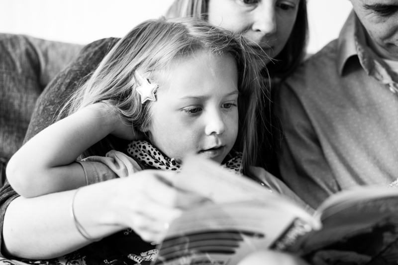Girl reading book on lady's lap
