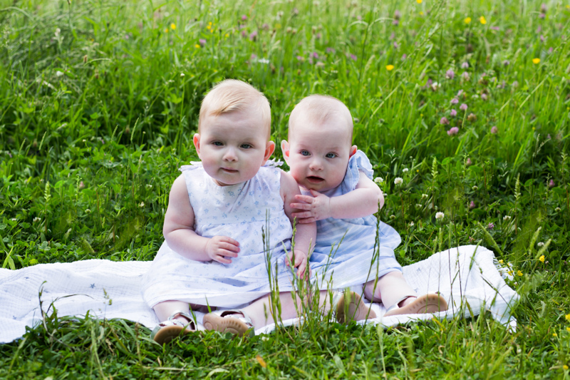 two twin babies sitting in the long grass