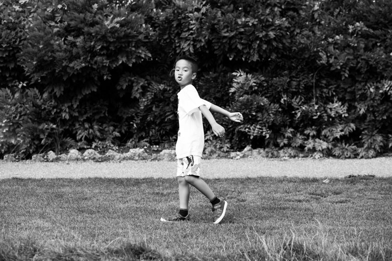 Boy walking across grass swinging his arms. 