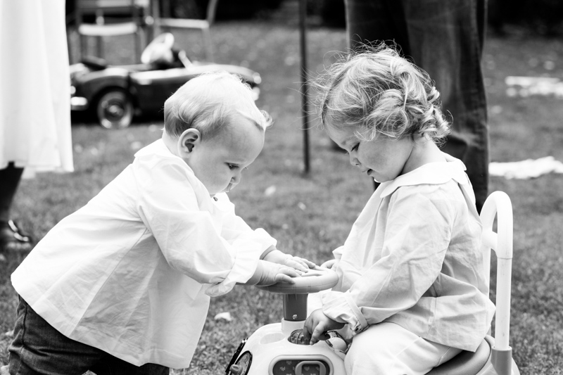 Two little girls playing with a toy car. 