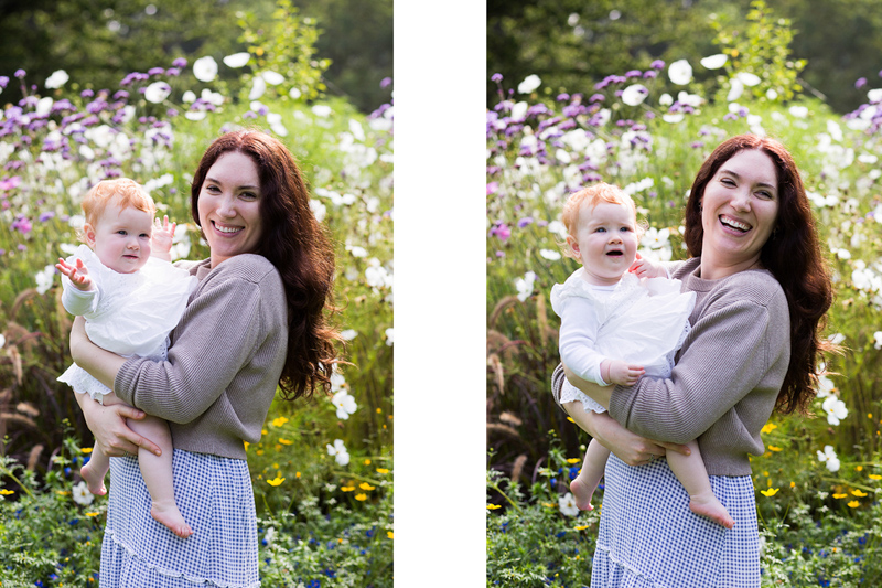Lady holding baby in front of flowers. 