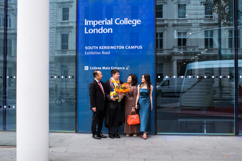 Family of four standing in front on "Imperial College London" sign. 