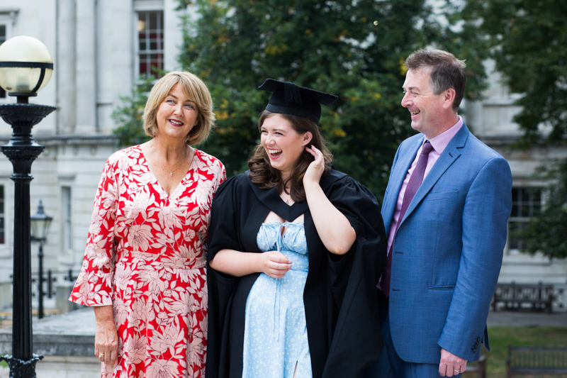 Mum, dad and graduating daughter laughing together. 
