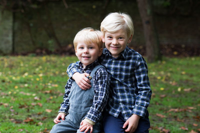 Two smiling boys, the older one hugging the younger one. 