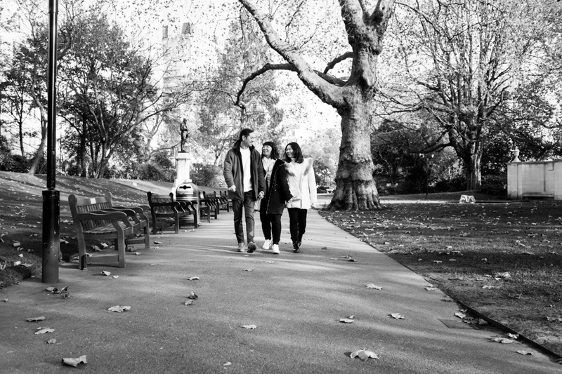 man and two ladies walking through the park. 