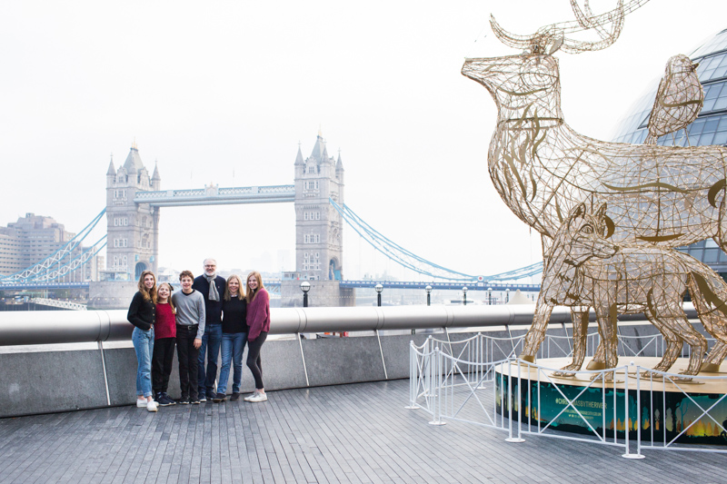 Family of six in front of Tower Bridge next to huge Christmas decoration.