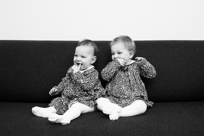 Two twin girls sitting on sofa. 