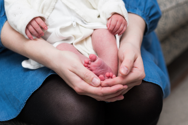 Lady's hands cradling baby's feet.