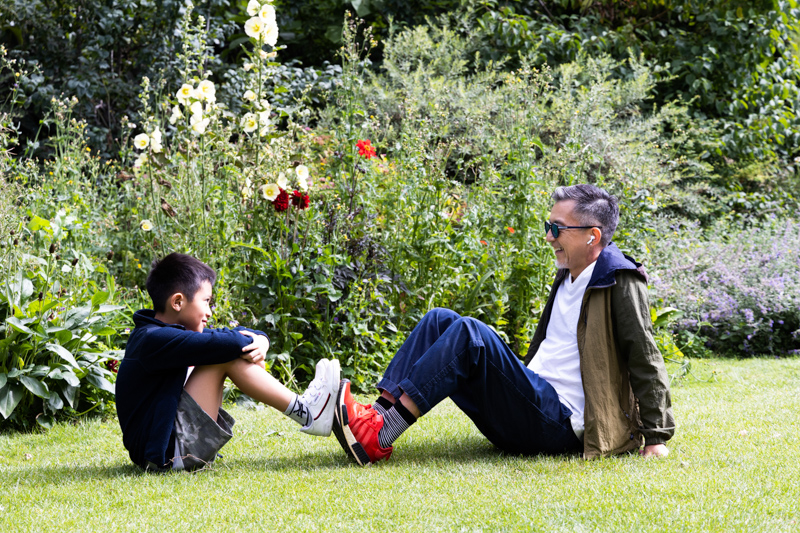 man and boy with their feet together sitting on the grass