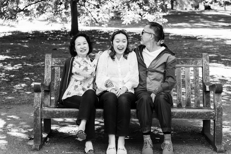 three family members laughing on a bench