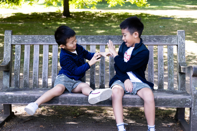 two boys playing together on park bench